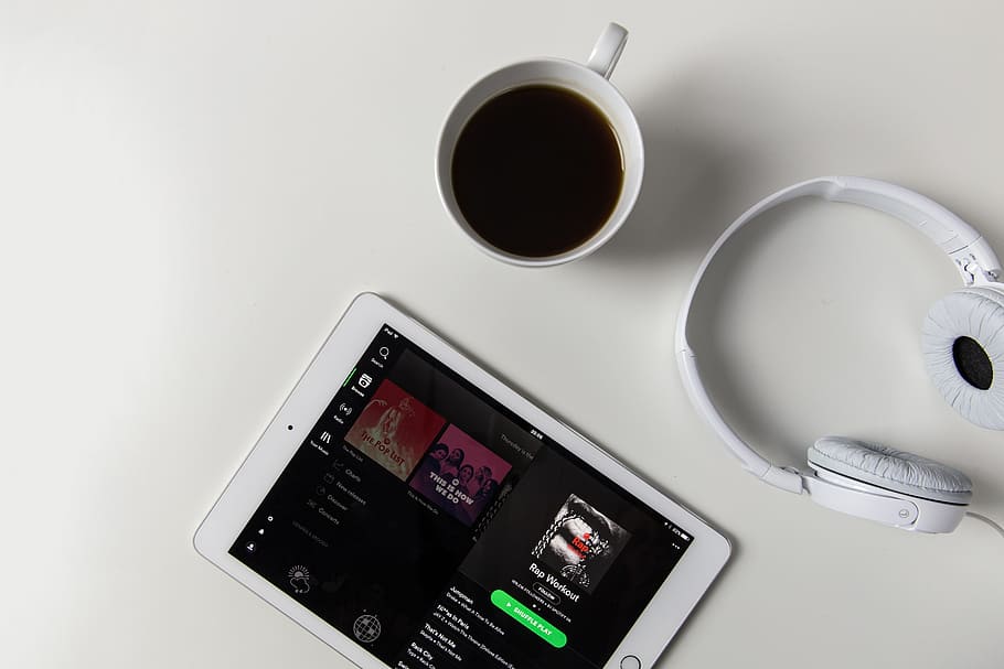 Headphones, coffee and iPad tablet with Spotify music app open on a white desk, HD wallpaper