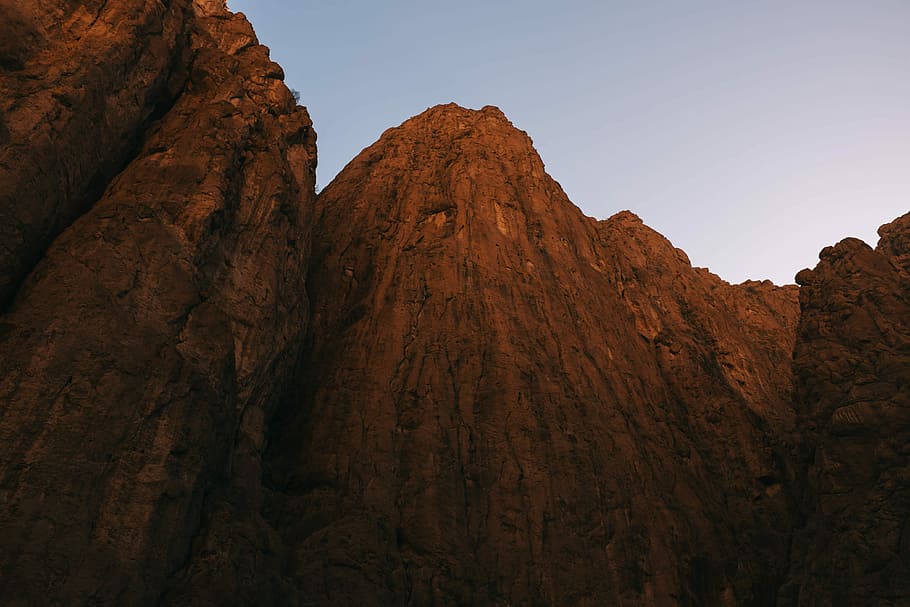 rock formation under blue sky, low angle photography of cliff at daytime HD wallpaper