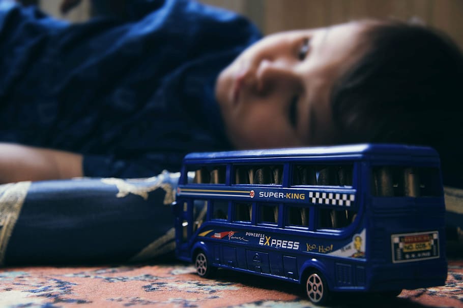 blue bus die-cast toy and boy force focus photography, sad child