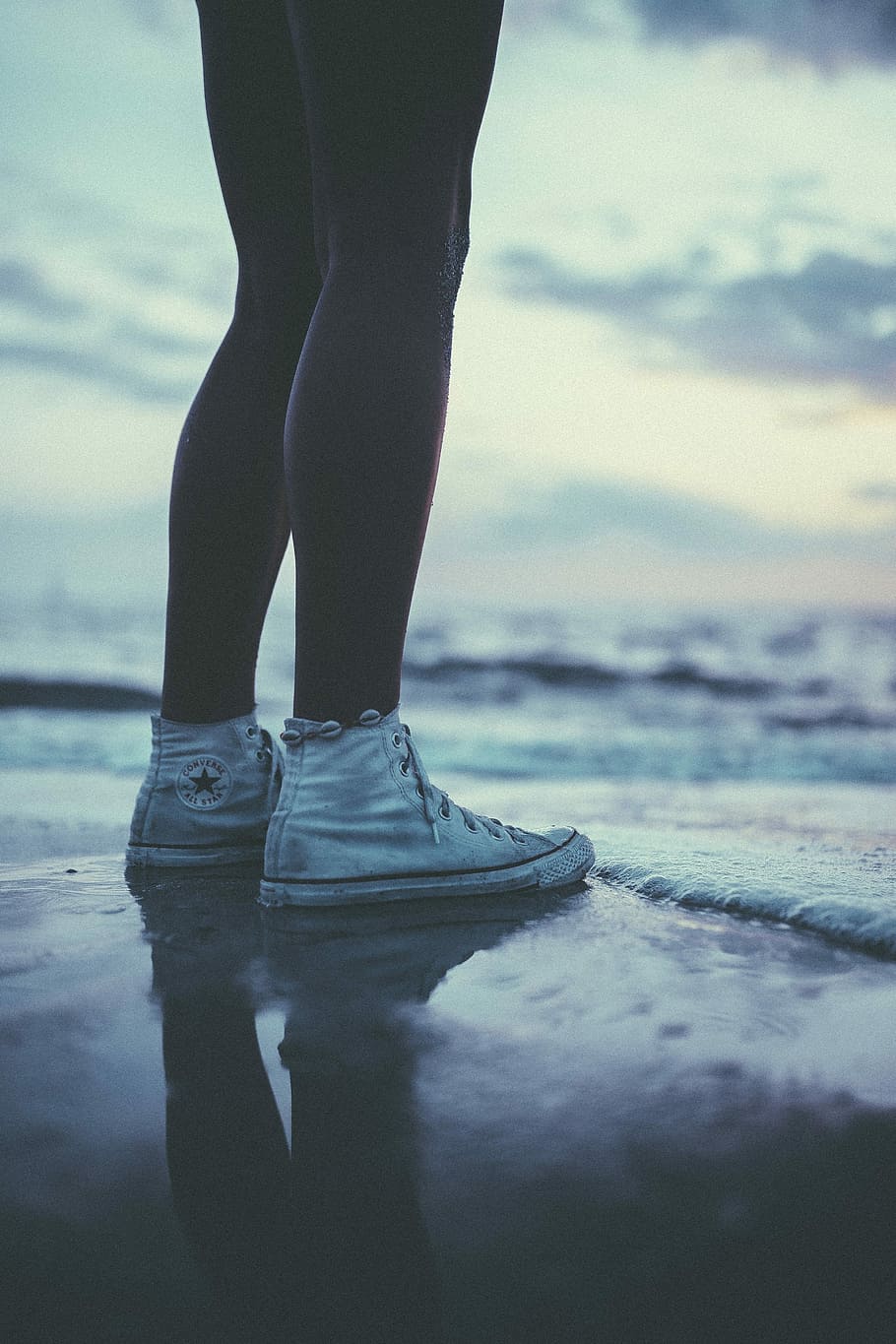 person wearing pair of white Converse All-star sneakers, worm's eye view of person standing at seashore HD wallpaper