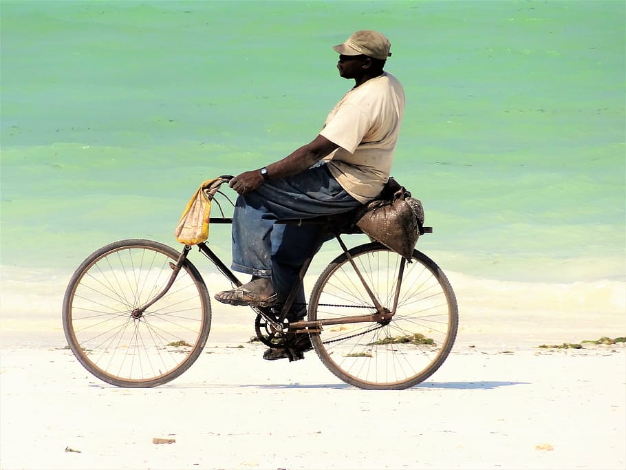 man in beige shirt and blue pants riding bike on shoreline HD wallpaper