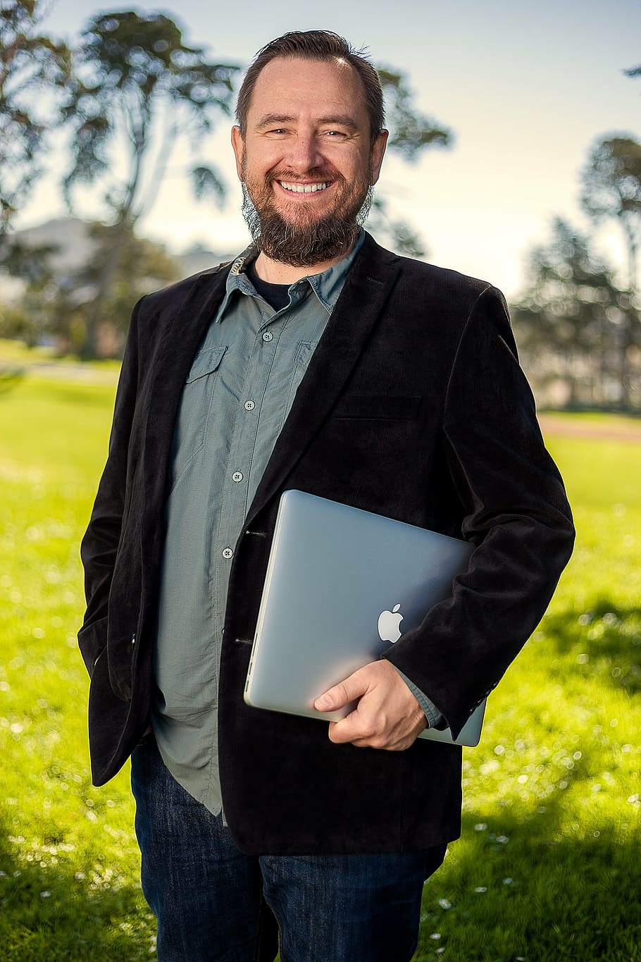 man in black coat holding silver MacBook, portrait, outdoor HD wallpaper