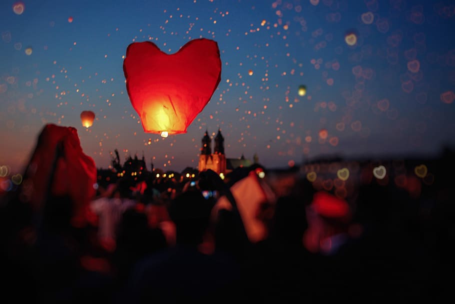 crowd of people flying heart lanterns in the sky, shallow focus photography of red floating lantern