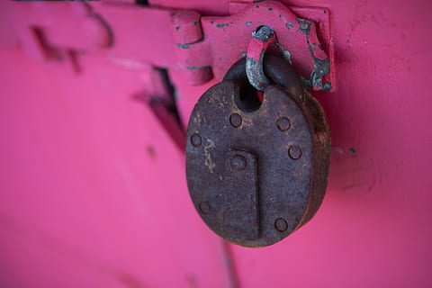 Close-up shot of a rusty lock captured against a vivid pink background HD wallpaper