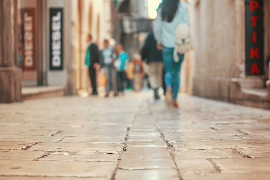 people walking on alley, tilt lens photography of woman wearing blue jeans and blue shirt walking on brick pavement HD wallpaper