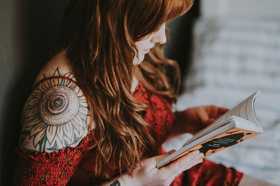 woman reading book, women's red top, caucasian, tattooed woman