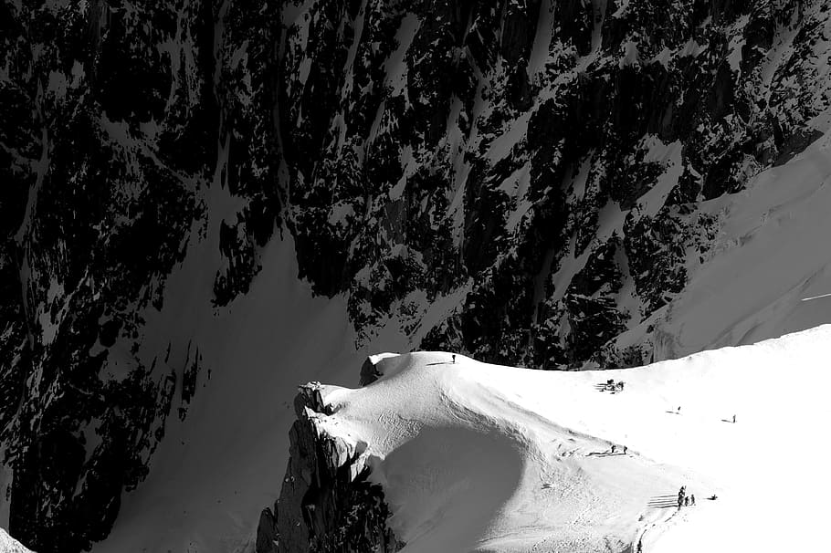 gray stone mountain covered by snow, aerial view photography of people standing on mountain cliff covered by snow during daytime HD wallpaper