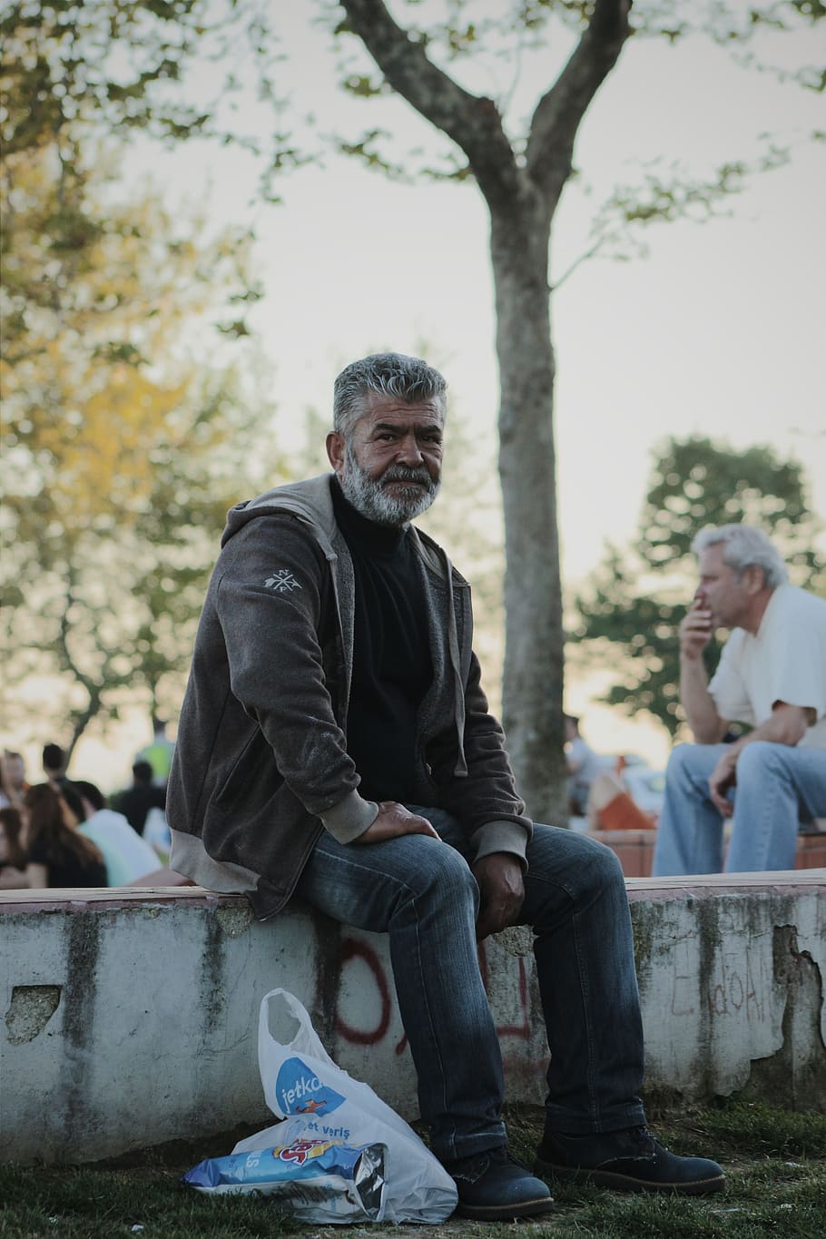 Man Wearing Gray Jacket Sitting on White Stone in Park during Day Time HD wallpaper