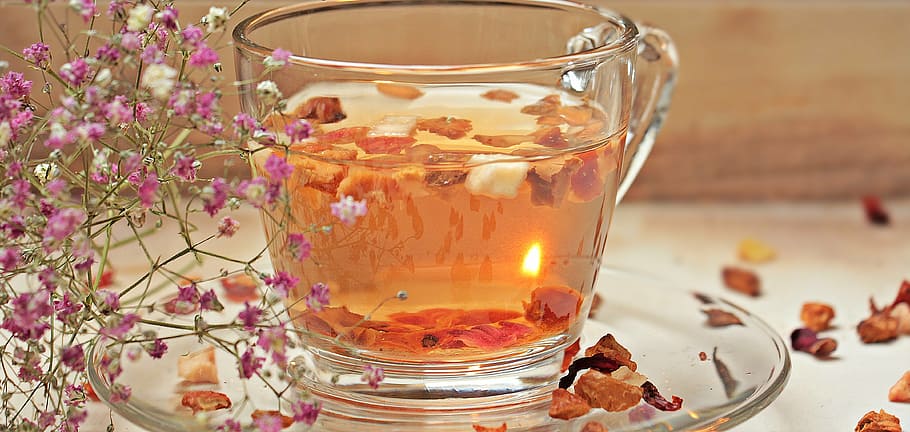 photo of filled clear glass teacup with saucer and flower petals HD wallpaper