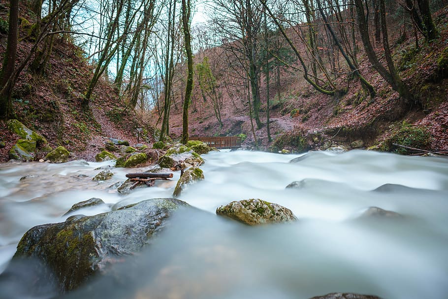 time-lapsed photography of body of water between trees on brown mountain, body of water between two soils HD wallpaper