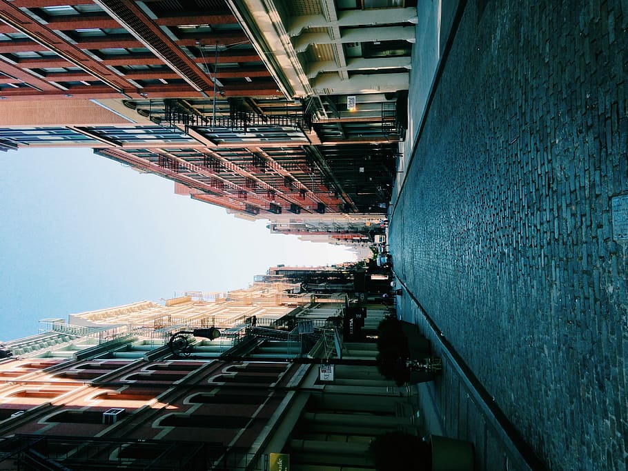 photo of road between brown buildings, gray concrete pavement surrounded by buildings HD wallpaper