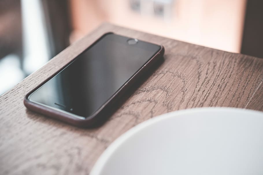 Black Smartphone on Wooden Table in Café, cafe, desk, iphone