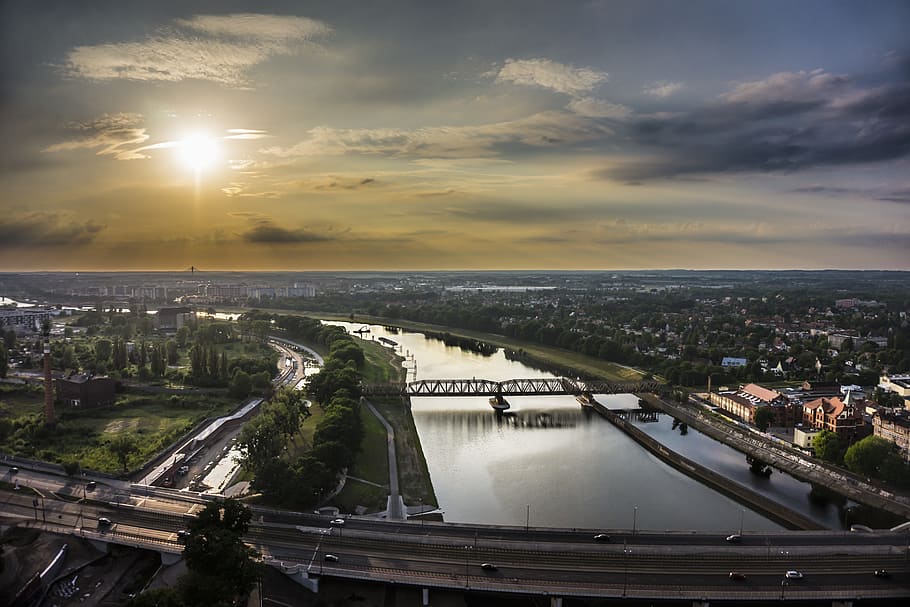 aerial photography of bridge, trees, and buildings under white clouds at daytime HD wallpaper