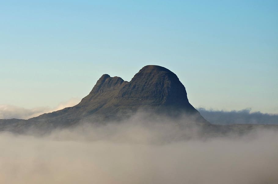 Magnificent Suilven rises above the morning mist, brown mountain covered with clouds