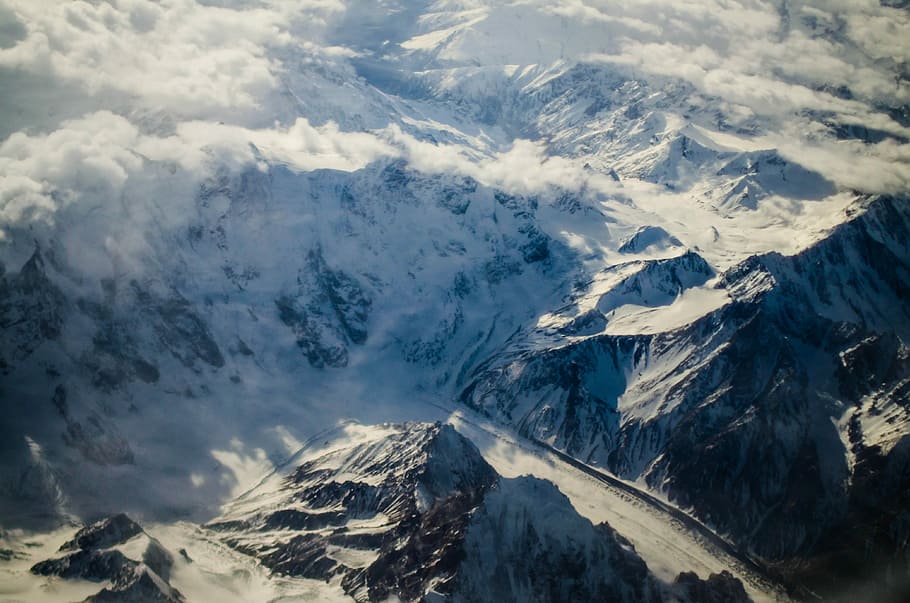 snow covered mountains under sunny sky, bird's eye photography of mountain cliff covered with snows HD wallpaper