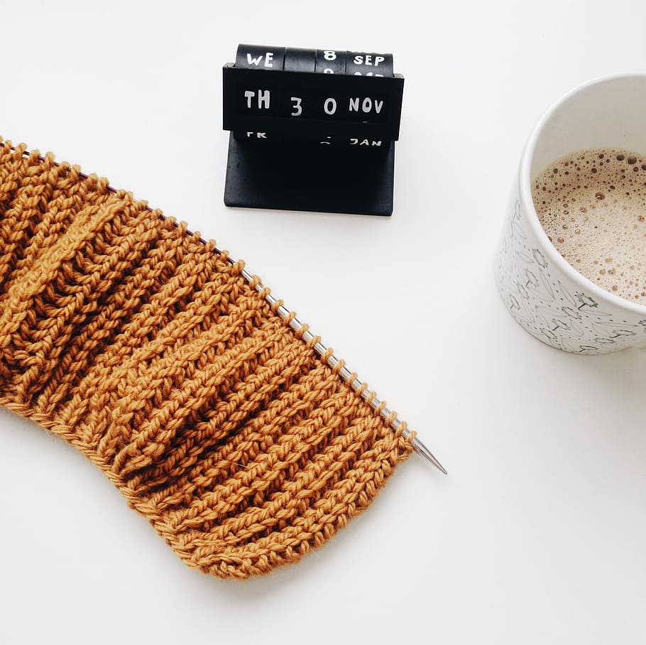 teacup beside knitted cloth, flat-lay photography of brown crochet textile, half-full disposable cup, and black desk calendar HD wallpaper