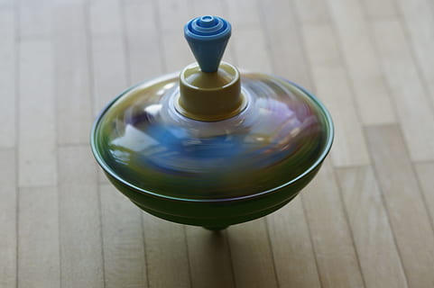 blue and green spin top spinning on brown surface, roundabout HD wallpaper