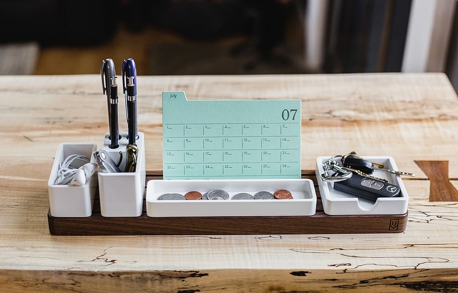 coin on tray beside pen organizer on table, white ceramic pen holder