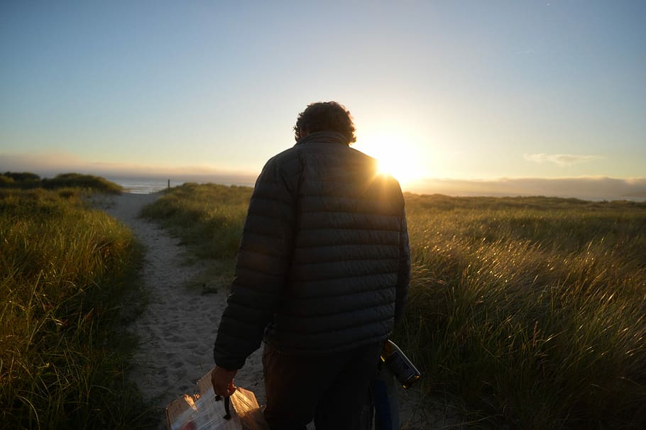 man walking across the road during sunrise, man walking on sand path during daytime HD wallpaper
