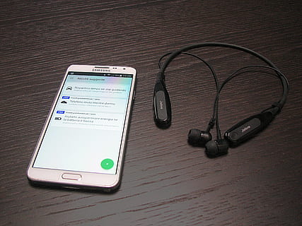 white Samsung Android smartphone beside stereo neckband headphones HD wallpaper