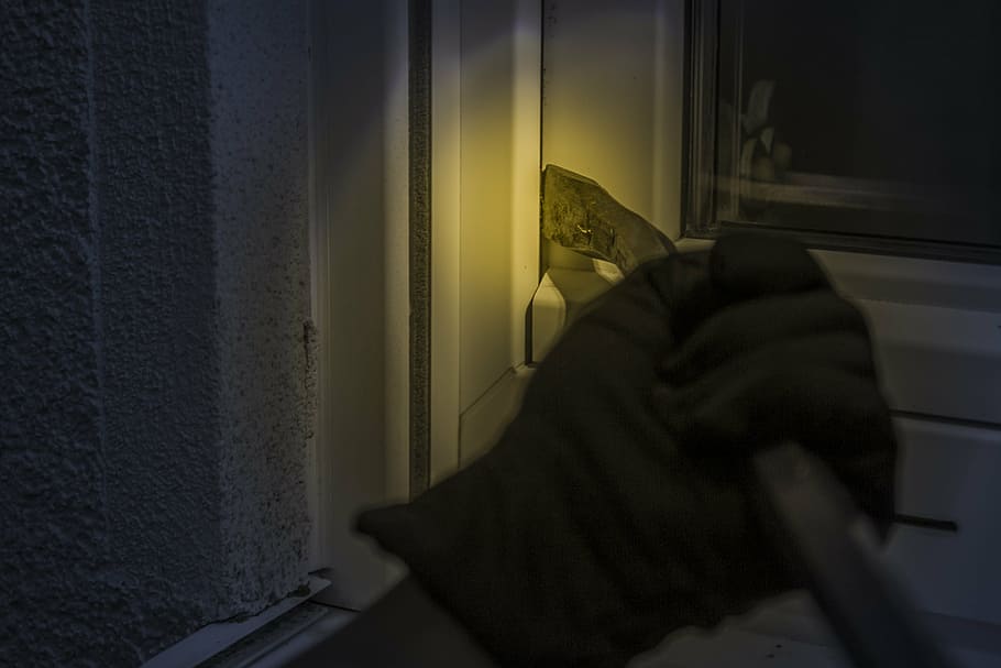 person holding black steel frame, burglar, at night, window, crowbar