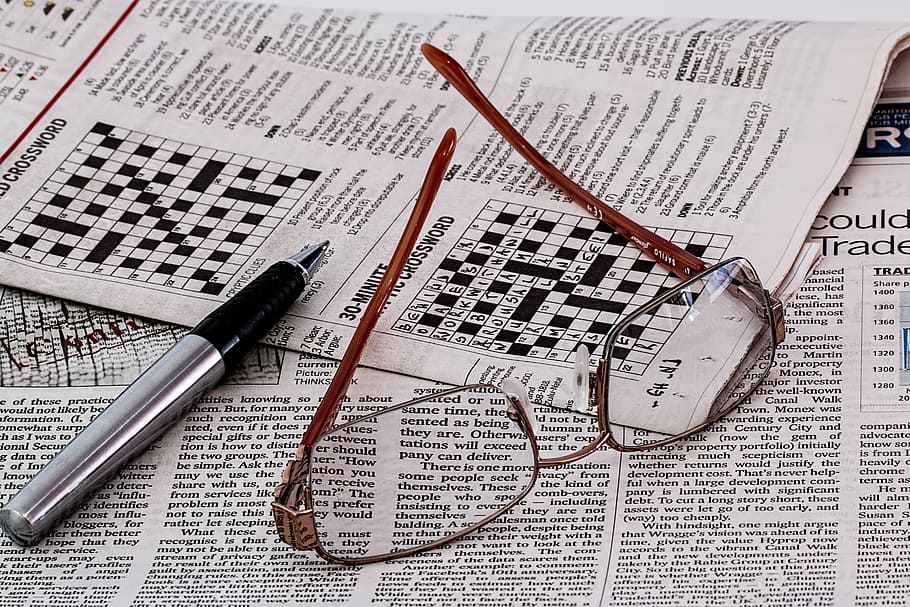 silver-colored framed eyeglasses beside ballpoint pen, newspaper