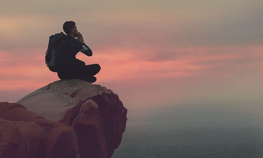 man sitting on mountain ledge at sunset, clouds, sky, travel