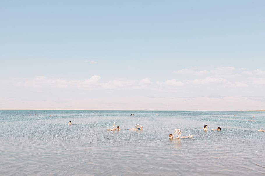 people swimming on sea under cloudy sky, people swimming on beach during daytime HD wallpaper