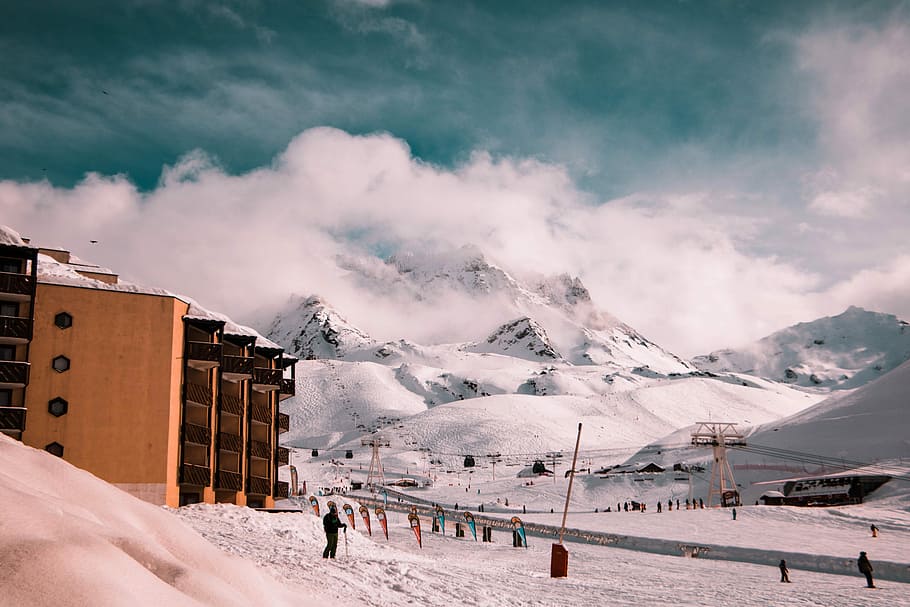 show-covered mountains during daytime, people walking beside asphalt road HD wallpaper