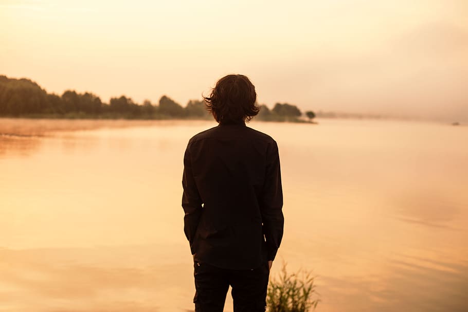 man in black long-sleeved top standing near body of water during daytime, HD wallpaper