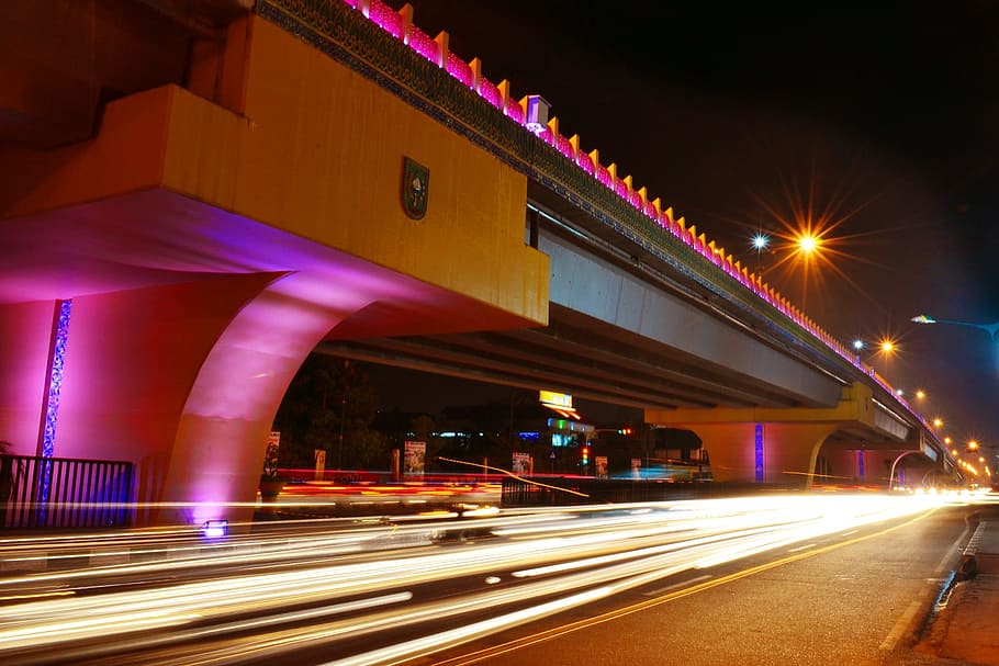timelapse photography of vehicle travelling on road below bridge at night time HD wallpaper