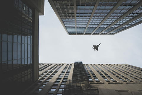 worm's view photo of fighter jet flying above building, worm's eye view of plane flying mid-air during daytime HD wallpaper