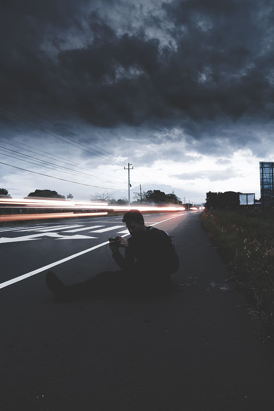 man sitting on road in time lapse photography, time lapse photography of man sitting on pave road under cumulus clouds HD wallpaper