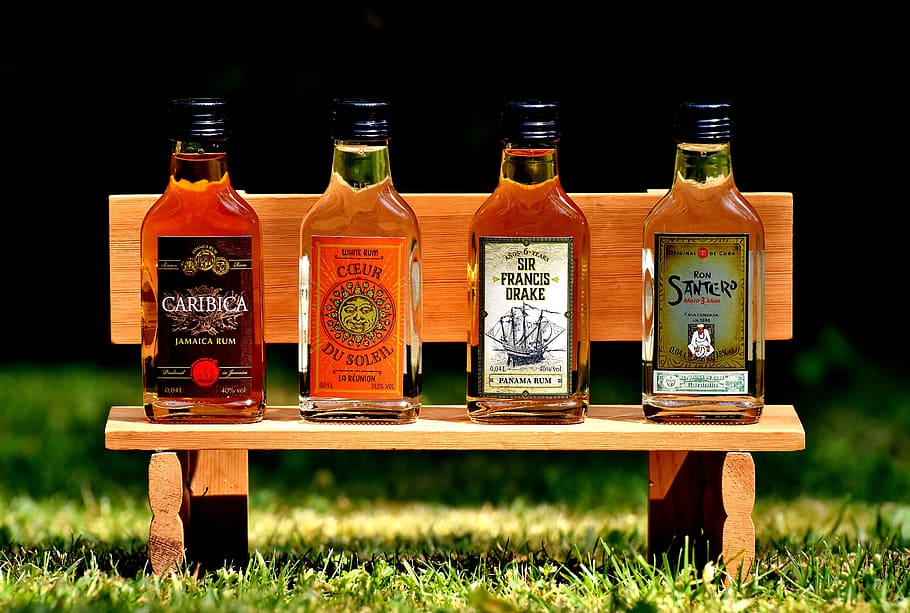 four beverage bottles on wooden bench, rum, alcohol, different origin