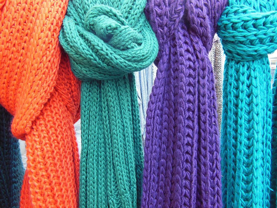close-up photo of four knitted scarves, green,orange, purple