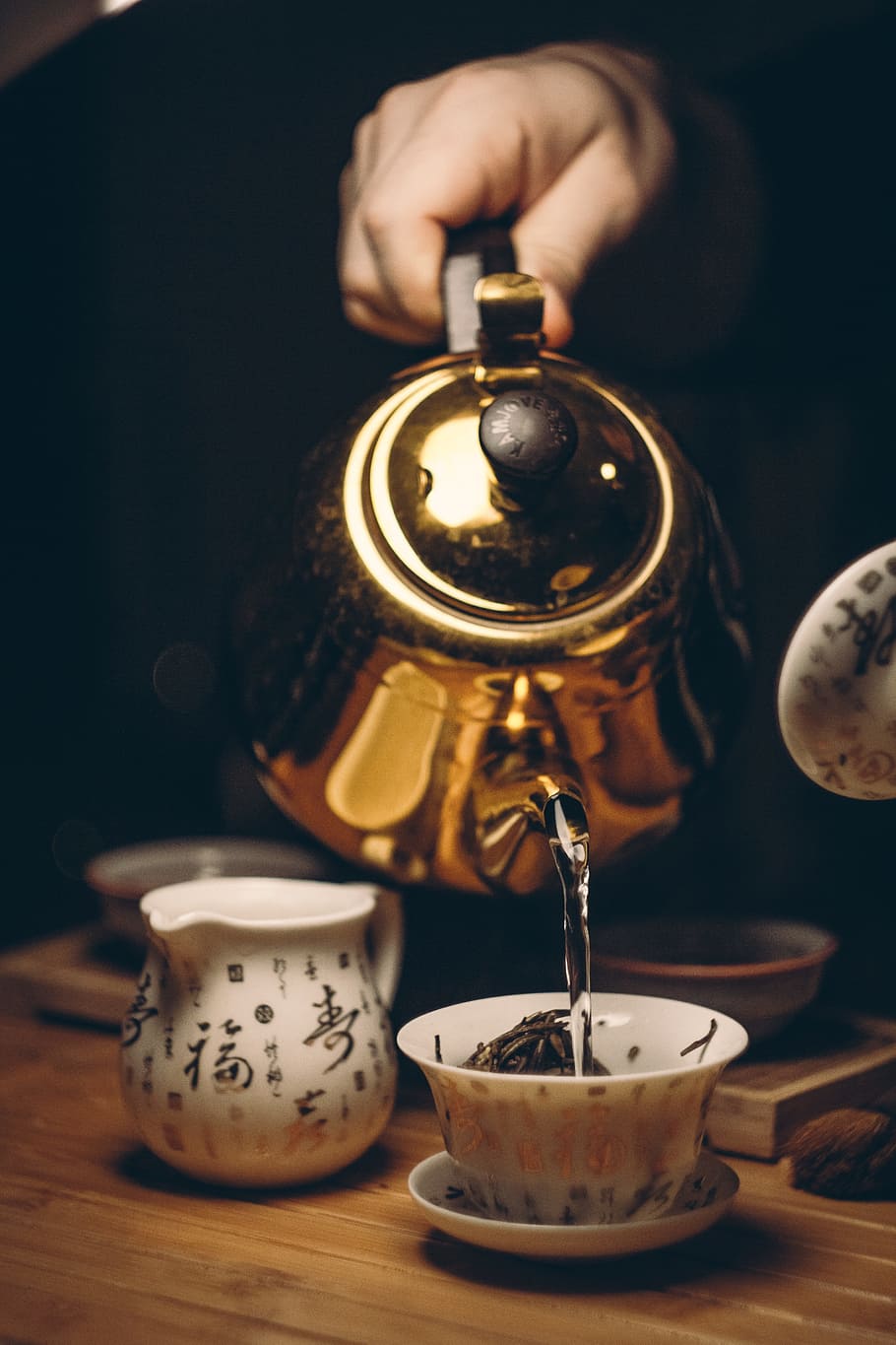 person holding brass kettle under white teacup on white saucer HD wallpaper