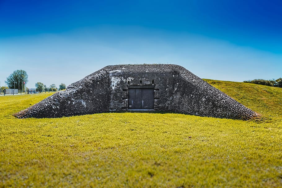 black concrete wall surrounded by green grass field under blue sky at daytime