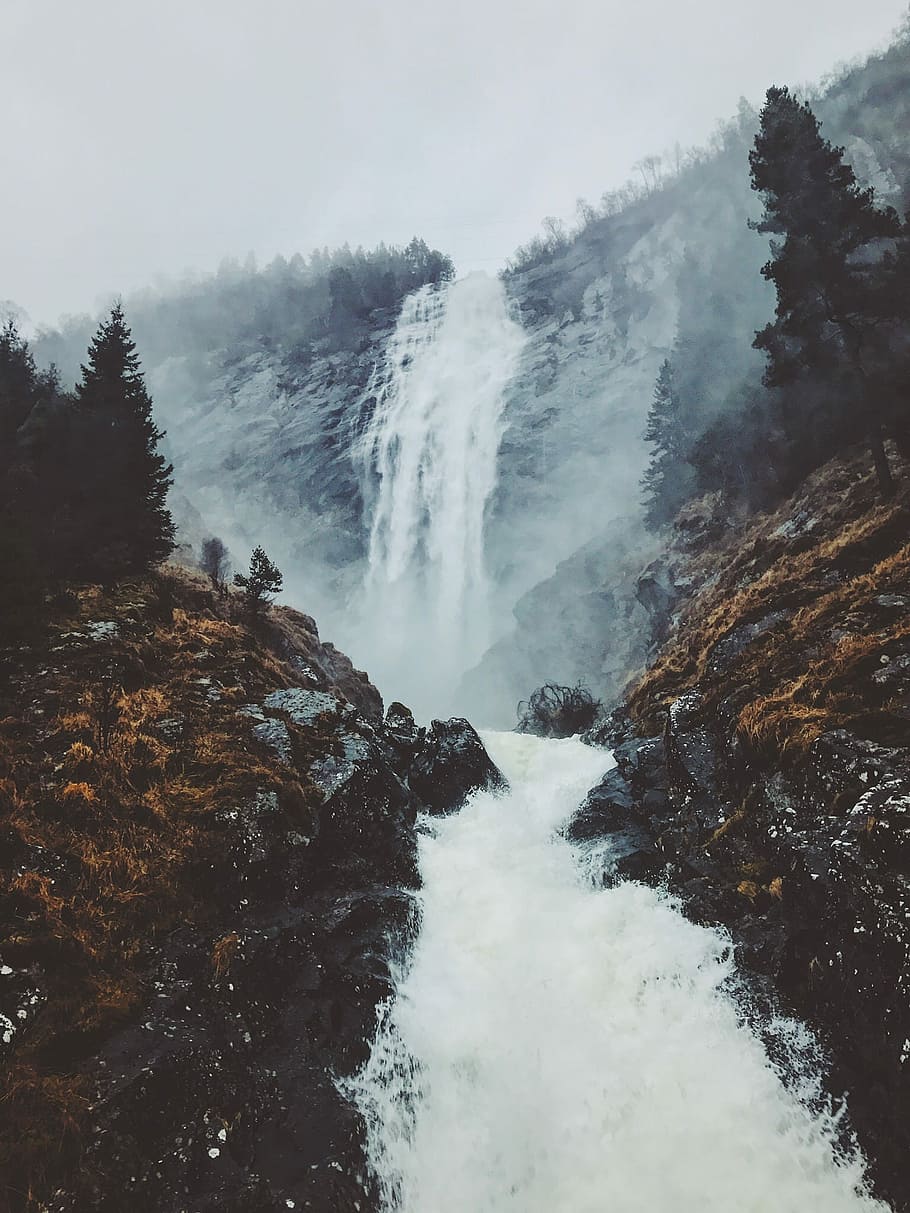 foggy mountain with falls, waterfalls flowing in between rocks and mountain during daytime HD wallpaper