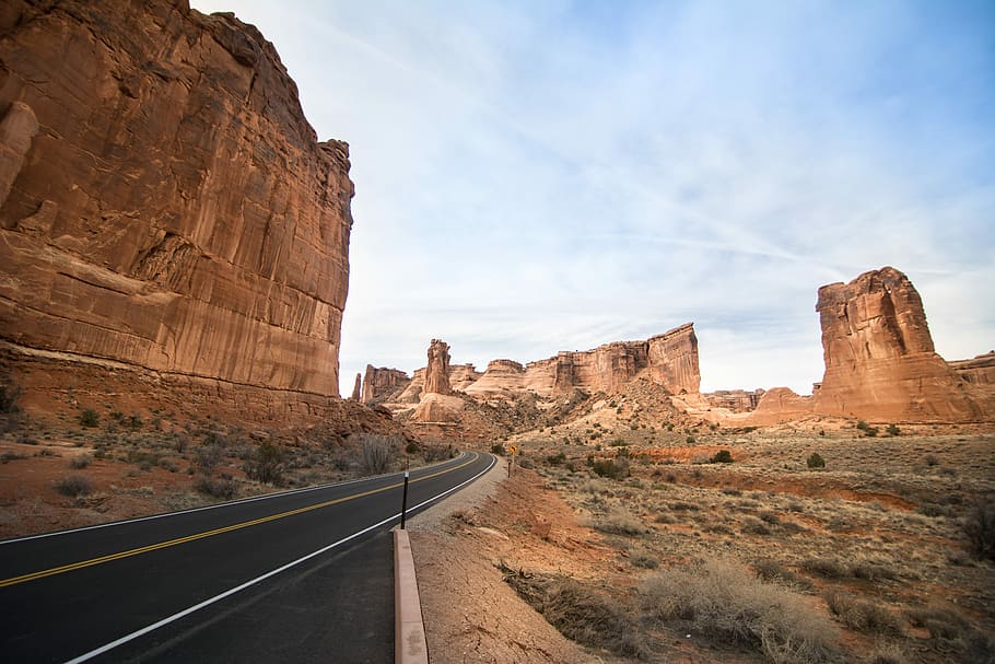 landscape photography of rock formation, desert and asphalt road during daytime HD wallpaper
