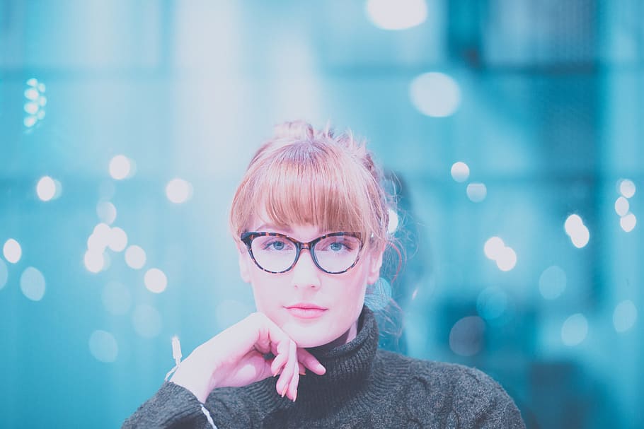 woman wearing gray turtle-neck sweater posing at camera, woman in gray turtleneck fabric tops with brown and black eyeglasses