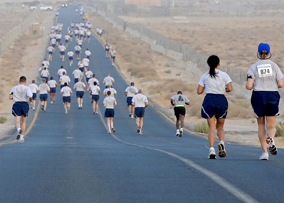 people walking across a road between a desert, runners, competition