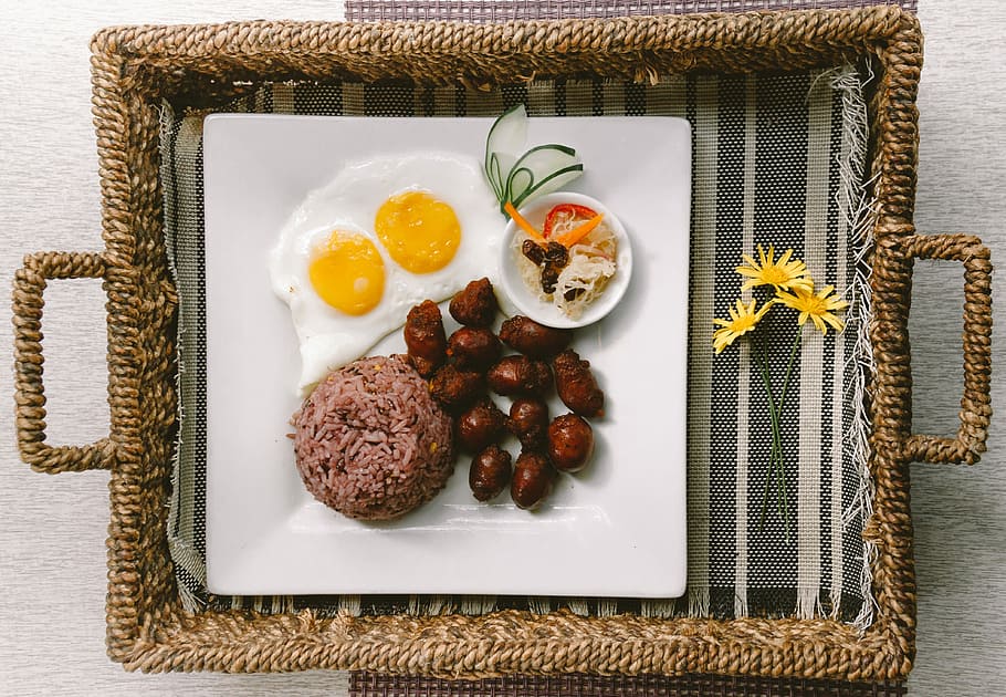 plate of foods on brown wicker tray, flat-lay photography of fried egg, meats, and rice platter on tray