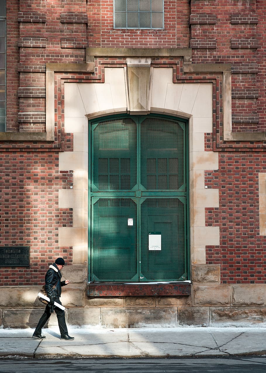 man walking beside the road, man passing near green door, building HD wallpaper