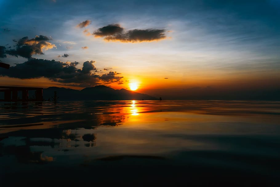 photography of sea across hill at sunset, dusk, sky, clouds HD wallpaper