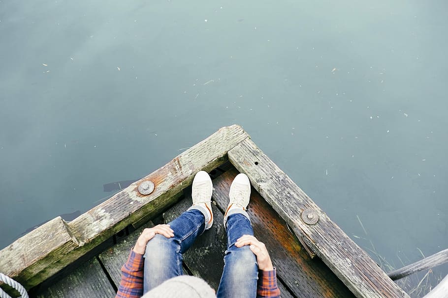 top view photo of person in denim pants sitting on brown wooden dock over body of water, HD wallpaper