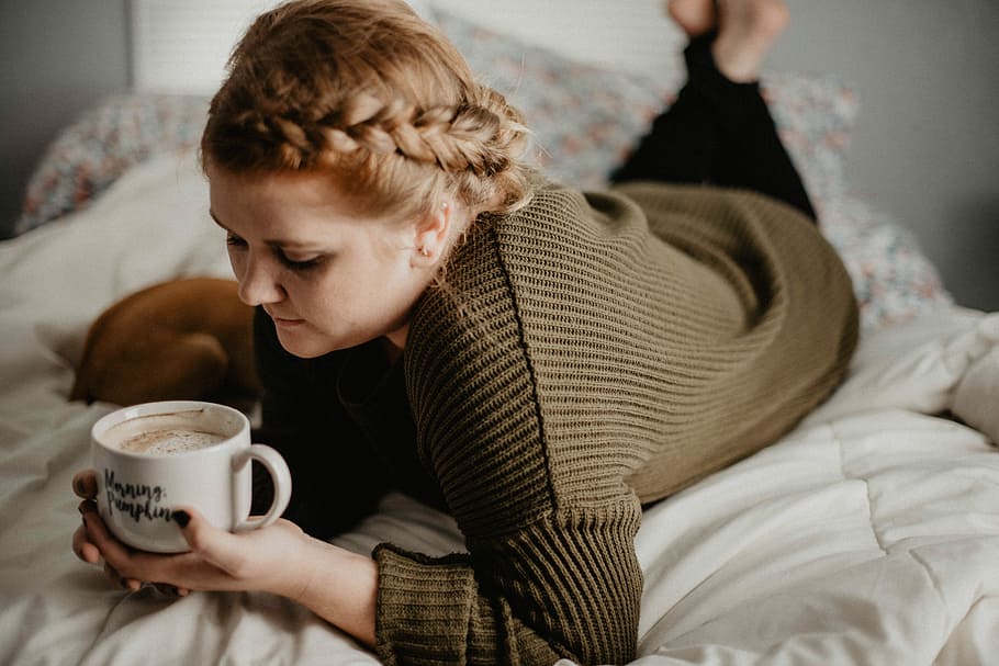 woman on bed holding white mug, woman holding ceramic mug while laying on bd HD wallpaper