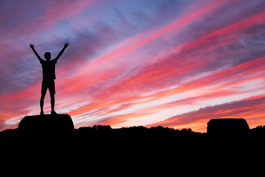 silhouette of man standing on high ground under red and blue skies, Reach out to the world