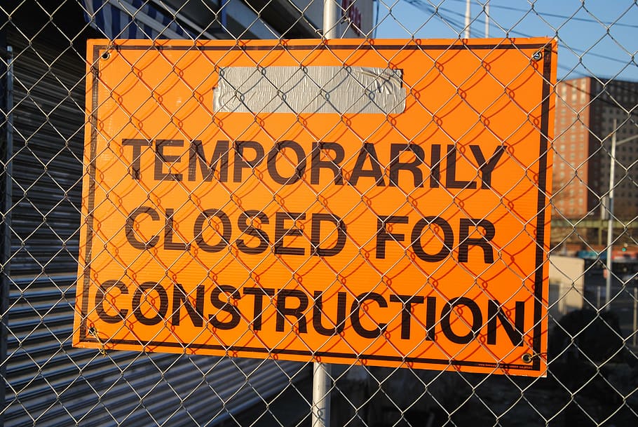 orange signage in front of fence, site, website, under construction