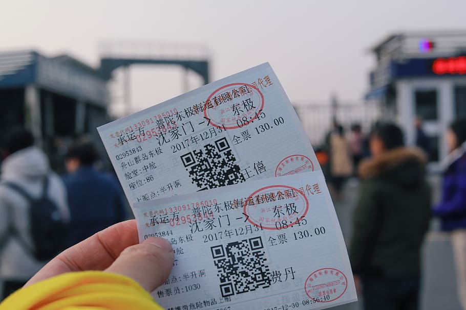 person holding two white tickets, person holding two tickets showing QR codes