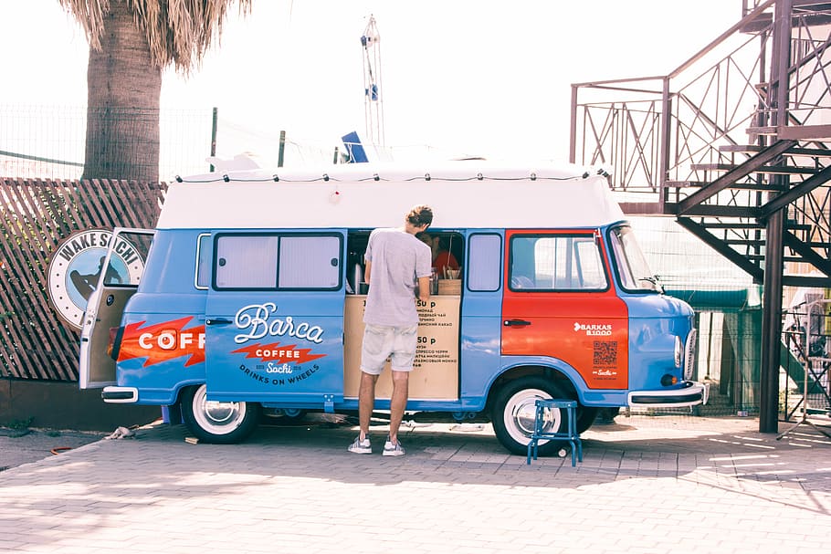 man standing near blue van during daytime photo, man standing in front of Barca Coffee van outdoor